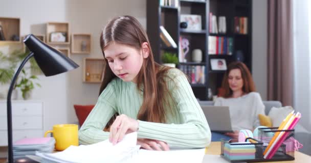 专心冷静的女孩在做家务 忙着工作的妈妈和平静的女儿在做家庭作业 父母和孩子都在房间里女学生学习书本 静止不动 小学概念 — 图库视频影像