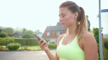 Genç beyaz bir kadının portresi telefonda yazıyor, eğitimden sonra tatmin oluyor. Sağlıklı bir yaşam tarzı için spor egzersizleri kavramı.