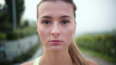 Sabahtan sonra sokakta koşarken kameraya bakan ciddi ve güzel kadının portre görüntüsü. Spor kıyafetleri giyen aktif spor koşucusu. Eğitim kavramı