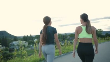 Çağdaş şehir caddesinde antrenman yaparken yolda yürüyen yorgun bayan arkadaşların arka görüntüsü. Spor konsepti