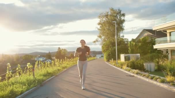 若いアスリートの女性が通りを走り 一生懸命トレーニングし レースやマラソンの準備をしています 健康的なランニングと屋外運動の概念 — ストック動画