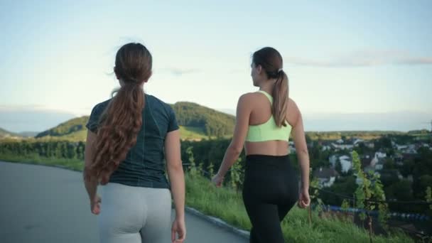 若い美しい白人女性がお互いに話をし 訓練後に歩いています 健康的なライフスタイルのためのスポーツ演習の概念 — ストック動画