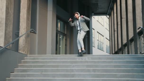 快乐的年轻的高加索商人从大城市建筑外的台阶上走下来 跳着滑稽的舞步 因为他有好消息或成功的合同 — 图库视频影像