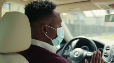 Sürücü koltuğunda direksiyonda oturan ve güzergahını düşünürken yola bakan koruyucu maskeli çok ırklı bir adam. Taşıma kavramı