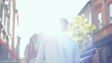 Avrupa 'nın eski şehir merkezinin caddesinde yürüyen beyaz tenli yakışıklı genç adam gün ışığında başka tarafa bakıyor. Şehir konsepti