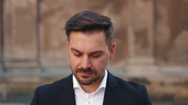 Yakışıklı bir iş adamı arka planda duran gözlüğünü takıp kameraya gülümsüyor. Kameraya bakan havalı sakallı adamın yüzünü kapatın.