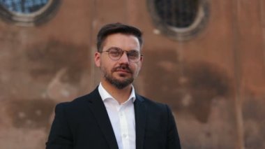 Arka planda duran gözlüklü yakışıklı iş adamı kameraya geniş bir gülümseme ile bakıyordu. Kameraya bakan havalı sakallı adamın yüzünü kapatın.