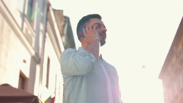 Genç Beyaz Bir Adam Şehirde Yürüyor Akıllı Telefondan Konuşuyor Neşeli — Stok video