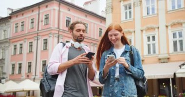 İki Kafkasyalı en iyi arkadaş sokakta dikilip akıllı telefon kullanıyor. Genç adam ve kadın mesajlaşıyor, sosyal medyada sohbet ediyor ve gülüyorlar. Teknoloji bağımlılığı, iletişim konsepti.