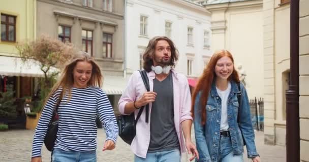 若い女性と男性の交換留学生が街を歩き 遠足をしています 親友は大学に行き 魅力的な建物を話し 指しています キャンパス 友情の概念 — ストック動画