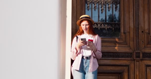 Молодая Рыжая Женщина Стоящая Возле Здания Опирающаяся Дверь Пьющая Кофе — стоковое видео