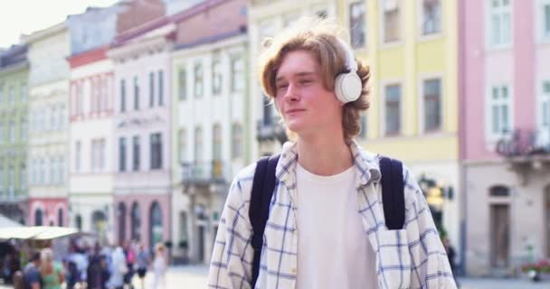 Schöner Männlicher Teenager Mit Kopfhörern Und Rucksack Der Durch Die — Stockvideo