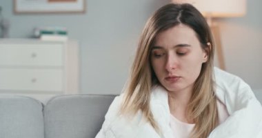 Oturma odasında battaniyenin altında oturan, burnuna tıbbi damlalar püskürten, hapşıran, Coronavirus 'lu genç beyaz kızı yakından çek. Coronavirüs belirtileri gösteren hasta bir kadın..