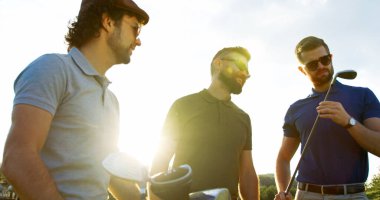 Portrait of three male golfplayers talking and looking at the golf club on the nice sunny day. Outside