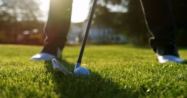 Close up of a ball being hitted by a golf club on the green golf pitch on a sunny summer day. Outside.