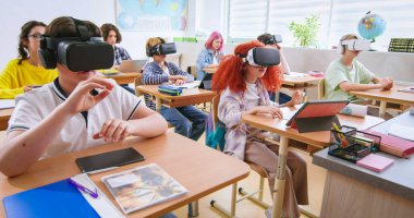 VR kulaklık takan zeki öğrenciler ve sınıfta gelecekteki teknolojilerle çalışıyorlar. Sanal gözlüklü kızlar ve oğlanlar okulda artırılmış gerçeklik deneyimi yaşadılar..