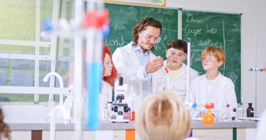 Beyaz ergen çocuklar kimya sınıfında erkek öğretmenlerle kimyasallar üzerinde deney yapıyorlar. Okulda öğrenciler için bir laboratuvar. Kapalı alanda. Tüpler ve sıvılar