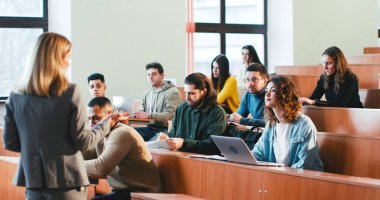 Üniversitede, elinde kağıtlarla, sınıftaki melez öğrencilere materyalleri anlatan kadın profesörün geçmişi. Kadın öğretmenlerin konuşmalarının arkasında. Öğretmenlik mesleği.