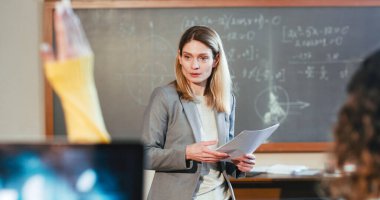 Neşeli, güzel, beyaz kadın profesör öğrencilerle konuşuyor ve sohbet ediyor. Bilgi edinme konsepti. Matematik dersinde sınıfla iletişim kuran gülümseyen bayan öğretmen..