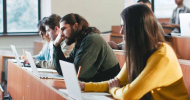 Sıkıcı öğrenciler, erkekler ve kadınlar üniversite dersinde masada oturup profesörü dinliyorlar. Eğitici bir kavram. Kapalı alanda. Üniversitede sıkıcı bir ders. Seminerde öğrenmek ve uyumak. Tembel herif..
