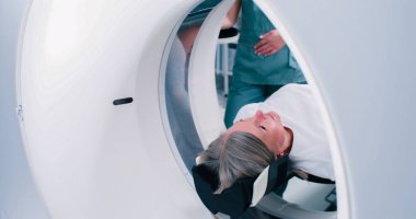 Kadının MRI kapsülünden çıkışının yakın plan çekimi. Hasta manyetik rezonans görüntüleme işlemini tamamladı. Tıp çalışanı CT taraması yapıyor. Kadın MRI tarama yatağında hareket ediyor..