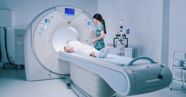 Hasta MRI işleminden önce doktordan tavsiye alıyor. Kadın tomografi tarama yatağında yatıyor. Kadın MRI tarayıcı kapsülüne giriyor. Kadın doktor tomografiyi inceliyor..