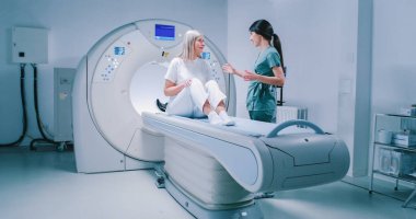 Doktor ve hasta tomografi testinin sonuçlarını tartışıyorlar. Kadın doktor tablet ve beyin taramalarını incelemek için kaydırma yapıyor. Kadın oturuyor ve dikkatle doktoru dinliyor..