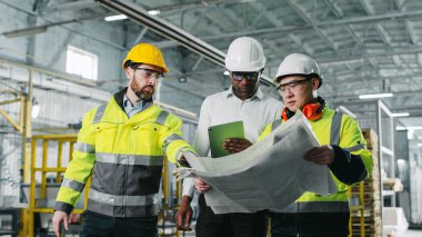 İş arkadaşları, iş sırasında endüstriyel imalat işyeri ile ilgili sohbet konuşmaları yapıyorlar. İletişim kuran orta yaşlı adamlar.