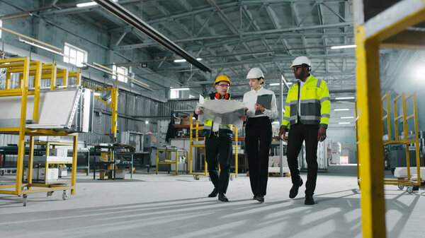 Portrait of cute young charming Asian engineer industry worker employee showing drawing to pretty adorable beautiful Caucasian female factory manager and his African-American colleague.