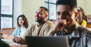 Genç ve mutlu melez öğrenciler üniversitedeki konferansta profesörle gülüp sohbet ediyorlar. Lisedeki öğretmenle gülümseyen ve konuşan adamlar. Bilgi edinme konsepti. Çok ırklı insanlar.