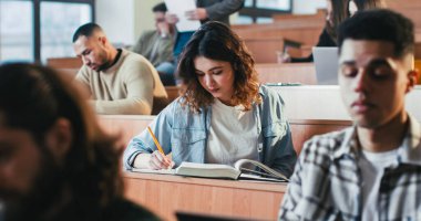 Üniversitede ders dinleyen, ders kitabı yazan ve kullanan beyaz bir kız öğrenci. Lisedeki seminerde kitap okuyor. Üniversite konsepti. Sınıfta ders çalışmak..