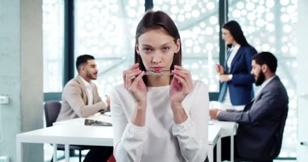 Ofisteki Modern Şirkette Kameraya Bakan Gözlüklü Özgüvenli Genç Bayan Işçinin — Stok video