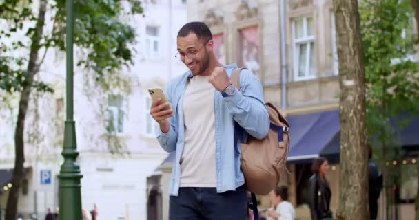 Szczęśliwy Młody Przystojny Mężczyzna Okularach Stojący Ulicy Smartfonem Czytający Dobre — Wideo stockowe