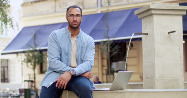 Şehir Merkezindeki Çeşmede Dizüstü Bilgisayarlı Gözlüklü Yakışıklı Bir Gencin Portresi — Stok video