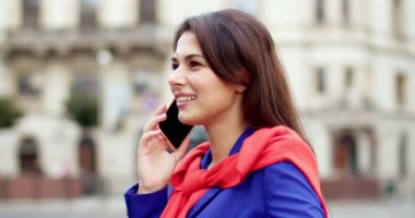 Şehir caddesinde gülümseyen ve cep telefonuyla konuşan güzel, genç, beyaz bir kadını yakından çek. Dışarı çıkın. Çekici stil sahibi bir kadın cep telefonuyla konuşuyor ve sohbet ediyor. Neşeli bayan arıyor..