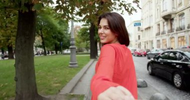 Romantik kavramı takip et. Açık havada. Beyaz, genç, güzel bir kadın sokakta yürüyor ve erkek arkadaşının elini tutuyor. Kasabada yürüyen ve erkek elini tutan oldukça mutlu bir kadın..