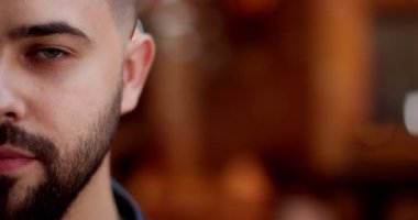 Gülümseyen, sakallı, genç ve neşeli erkek yüzünün yarısını kapat. Sokaktaki mutlu yakışıklı adamın portresi. Açık havada. Mutluluk duyguları ve mutluluk kavramını ifade etmek. Işıkların bulanık arkaplanı.