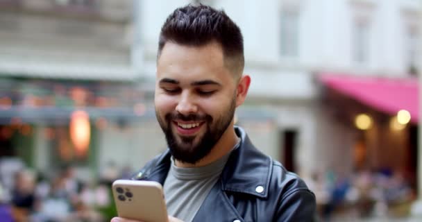 Közelkép Boldog Fiatal Jóképű Mosolygós Férfi Bőrdzsekiben Sms Mobiltelefonján Üzenetet — Stock videók