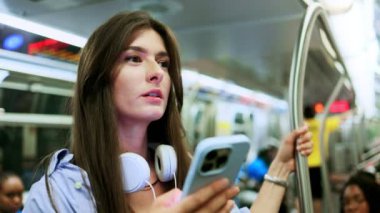 Esmer genç bir kadın, yeraltı treninde seyahat ederken internet üzerinden müzik dinliyor, podcast yapıyor ve sohbet ediyor. Metroda cep telefonunda mesaj yazan gülümseyen güzel bir kızın portresi..
