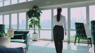 İş kadını konuşuyor, akıllı telefon şehir manzaralı, ofis arka planında. Modern ofiste büyük pencereli genç bir bayan cep telefonuyla konuşuyor..