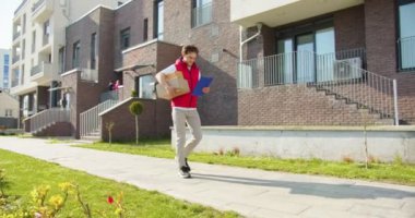 Beyaz erkek kurye caddede yürüyor ve yiyecek getiriyor. Paket taşıyan teslimatçı, süpermarketten gelen yiyeceklerle dolu karton kutular ve sipariş detaylarıyla kağıda bakıyor. Alışveriş konsepti