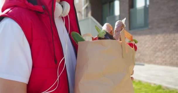 披着医疗面罩的白人年轻男性信使在街上把装有食物的纸袋交给他的女客户 男人在户外给女顾客送食品 — 图库视频影像