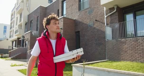 白人年轻人 送货员穿过街道 提着装有披萨的纸盒 外带包裹的英俊男子信使 — 图库视频影像