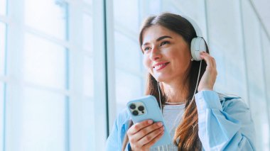 Havaalanında uçuşunu bekleyen tatlı ve tatlı beyaz kadın. Çevrimiçi akıllı telefon sohbetini kullanan çekici ve çekici genç bir bayan. Uçak konseptiyle seyahat.