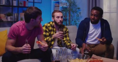 Üç neşeli, mutlu melez erkek en iyi arkadaş pizza yiyor, içiyor, konuşuyor ve akşam evde birlikte eğleniyorlar. Erkekler futbol maçı izler kanepede oturur spor kanallarını izlerler.