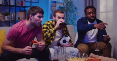 Mutlu, genç, çoklu etnik erkek arkadaşlar pizza yiyor, içki içiyor, sohbet ediyor akşam evde toplanıp maç izliyorlar. Erkekler spor kanalını izliyor. Hayranlar konsepti