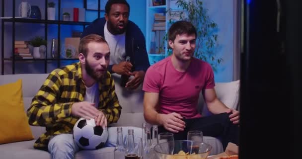 Három Fiatal Érzelmes Többnemzetiségű Férfi Csevegett Egymással Esténként Kanapén Focimeccset — Stock videók