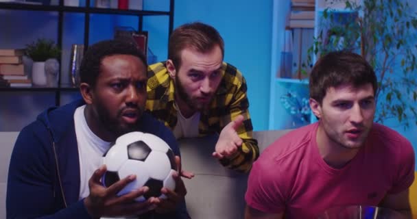 心情烦躁的混血男性好友深夜坐在公寓沙发上 在体育频道前看足球比赛 对比赛结果不满意 最受欢迎的足球队输了 靠近点 — 图库视频影像