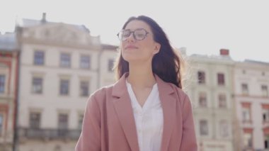 Kadın yüzü. Güzel saçlı güzel bir kızın düşük açılı portresi kameraya gülümsüyor, kendinden emin görünüyor, saçını düzleştiriyor ve şehir yaşamından zevk alıyor. Gerçek insanlar dizisi konsepti