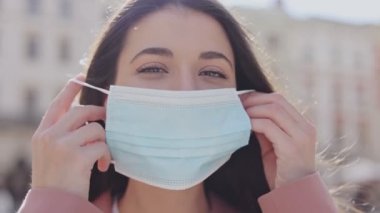 Güneşin doğuşunda şehir merkezinde koruyucu yüz maskesi takan esmer beyaz kızın portresi. Koronavirüs salgını COVID-19, salgın ve sağlık konsepti